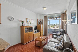 Ein Wohnzimmer mit Sofa, Couchtisch, Holzschrank und Fernseher.