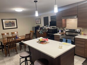 Una cocina moderna con armarios de madera, una isla central, un comedor con sillas y un refrigerador.