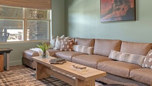 Ein Wohnzimmer mit einer Couch, einem Couchtisch und einem Fenster mit Jalousien.