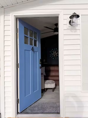 Una porta blava amb el número 4, un ventilador de sostre i una làmpada fixada a la paret.