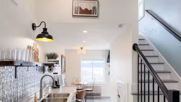 A kitchen with a marble countertop, stainless steel sink, and a black pendant light. - Incredible Lake & Mtn Views - Loft Vibes Getaway! (Tilton)