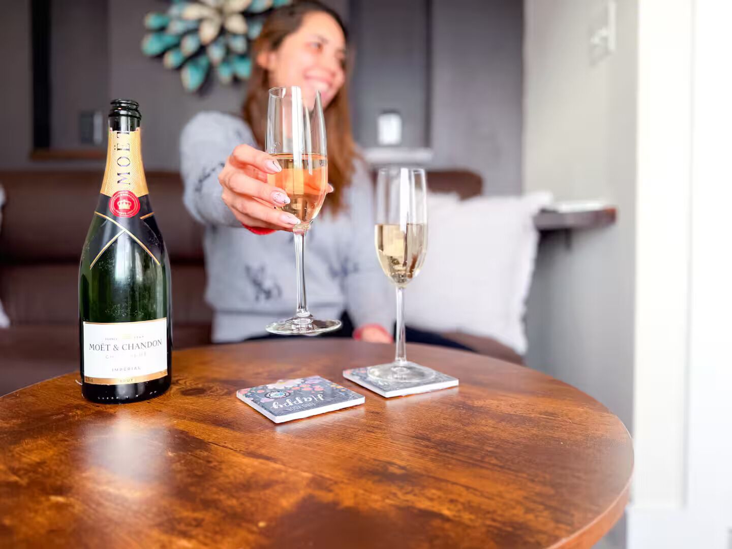 A bottle of Moët & Chandon champagne, two glasses, and a deck of cards on a wooden table.
