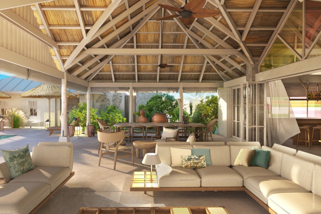 An outdoor lounge area with a high ceiling, wooden beams, and a thatched roof. There are multiple seating areas, including a sofa and chairs, and a dining table with chairs.