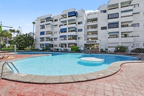 Una piscina con un área circular de hidromasaje, rodeada por un deck con baldosas rojas.