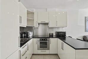 A modern kitchen with white cabinets, a stainless steel oven, a black countertop, and a microwave. - Vacation Apartment 'Iguazu Yumbo - Two Bedroom Apt' with Wi-Fi (Maspalomas)