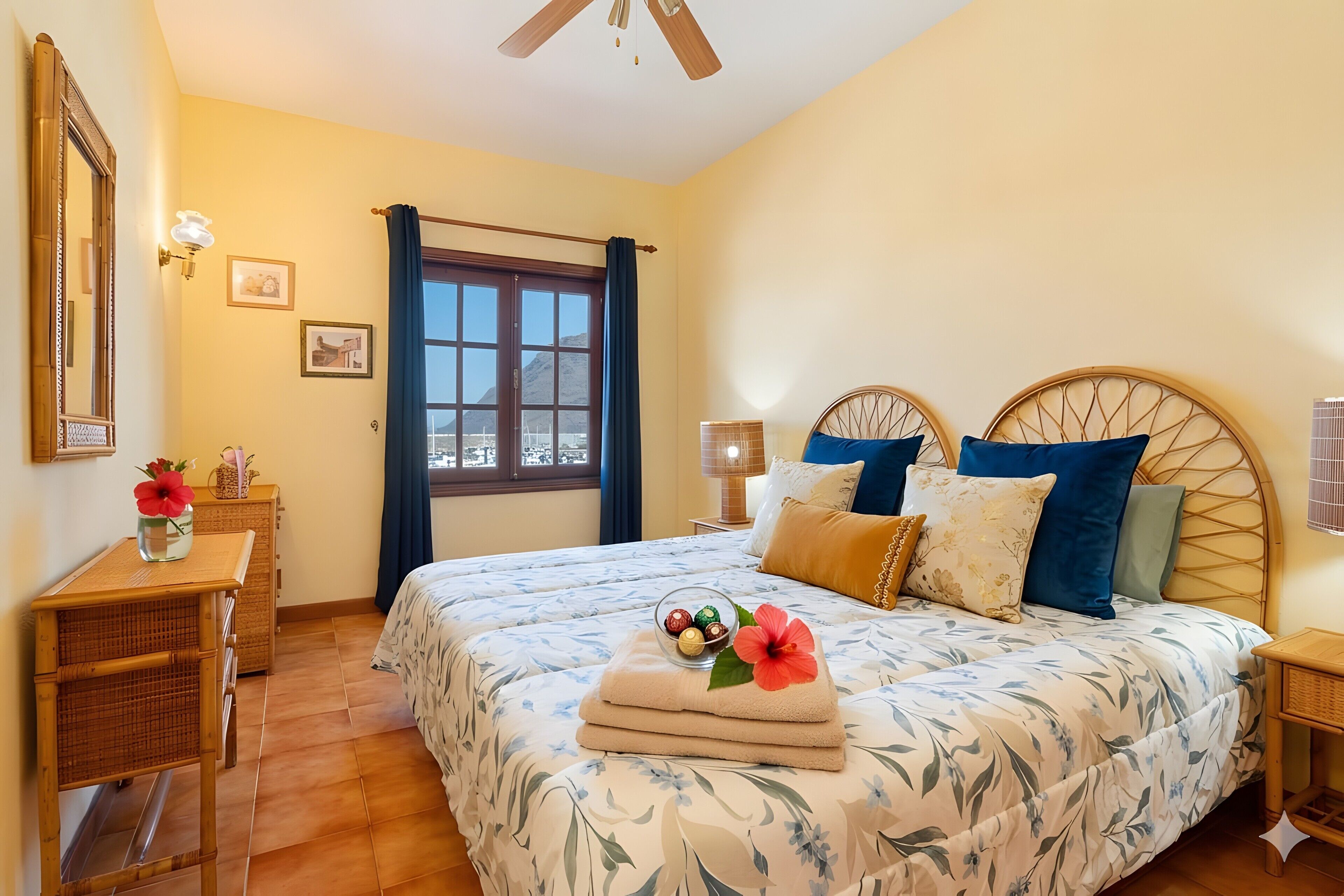 Ein Hotelzimmer mit Bett, Schreibtisch, Fenster und Deckenventilator.