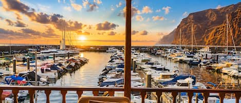 A balcony with a view of a marina during sunset.