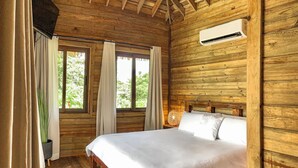 Camera da letto in una baita di legno con un letto, tende, una pianta in vaso e un condizionatore d'aria.