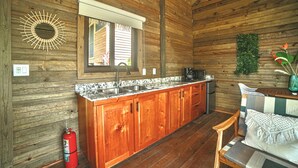 Interno di una baita in legno con cucina, mobili in legno, una finestra, un estintore e un'area pranzo.