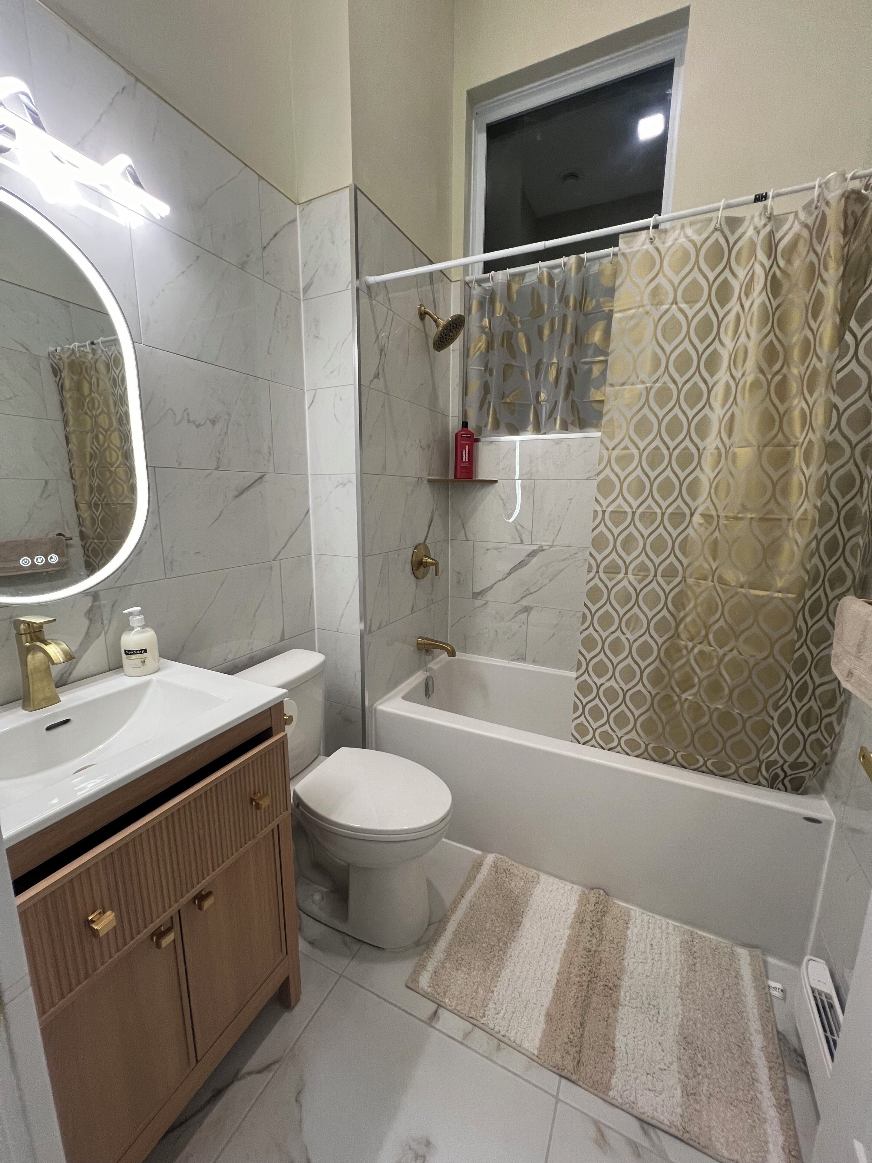 Une salle de bain comprenant une baignoire, des toilettes, un meuble-lavabo avec un miroir et un espace douche.