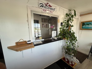 A reception desk at Hillcrest Motel with a sign, a plant, and a welcome sign.