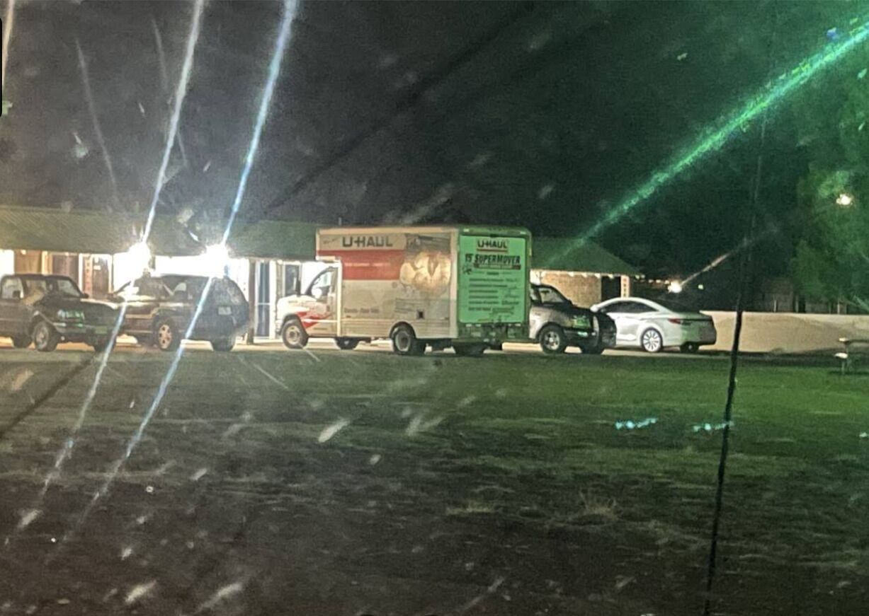 A U-Haul truck parked in a lot with several cars.