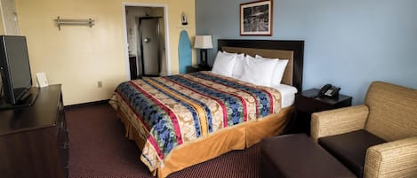 Habitación de hotel con cama, escritorio, silla, teléfono y ventilador de techo.