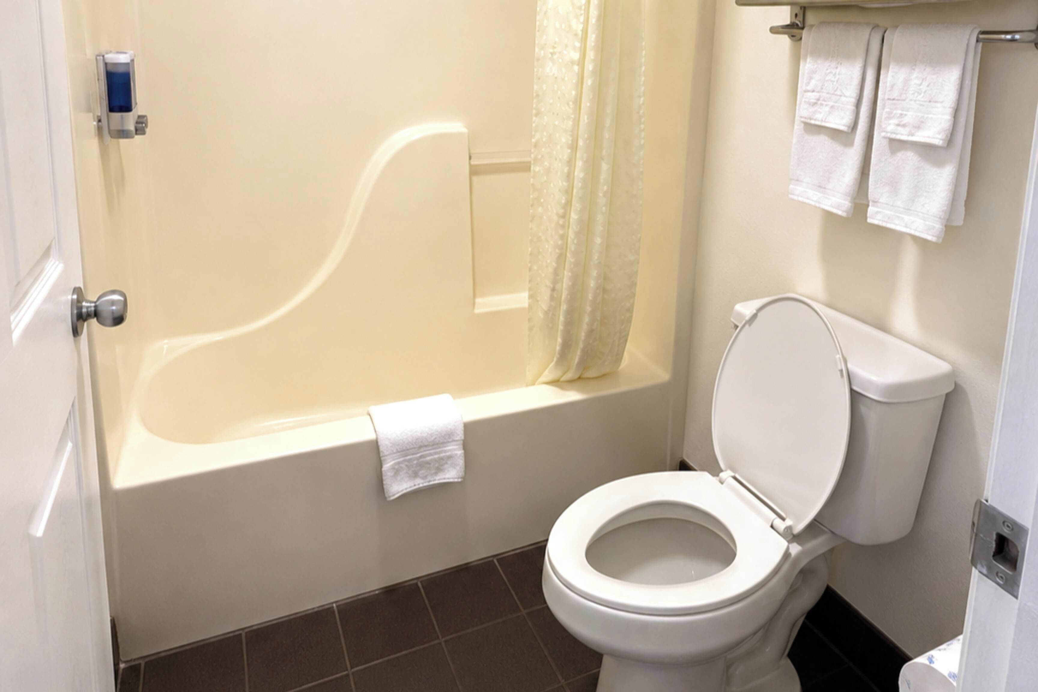 A bathroom with a bathtub, toilet, and a shower curtain.