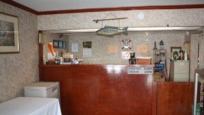 A reception desk with a wooden counter, a clock, and various informational signs. - Townhouse Motor Lodge Springfield Oh (Springfield)