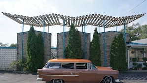 A vintage car parked in front of a building with a stone facade and a wooden pergola. - Townhouse Motor Lodge Springfield Oh (Springfield)
