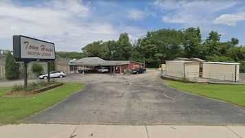 A motel with a sign reading '7own House Motor Lodge,' a parking lot, and a fenced area with buildings.