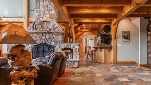 A cozy interior with a stone fireplace, wooden beams, a leather sofa, and a herringbone-patterned floor. - Luxury Mountain Estate | Spectacular Views (Sweden)