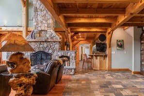 A cozy interior with a stone fireplace, wooden beams, a leather sofa, and a herringbone-patterned floor. - Luxury Mountain Estate | Spectacular Views (Sweden)