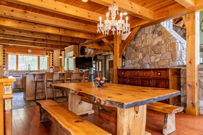 A rustic interior with a large wooden dining table, stone fireplace, and wooden beams. - Luxury Mountain Estate | Spectacular Views (Sweden)