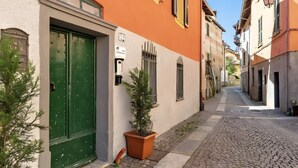 Una stretta via acciottolata fiancheggiata da edifici, con una porta verde e un vaso con una pianta.