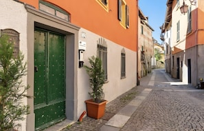 Una estrecha calle empedrada con edificios a ambos lados, una puerta verde y una planta en maceta.