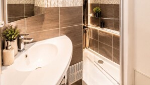 A modern bathroom with a large mirror, a white sink, a shower with a glass door, and a small shelf with toiletries. - Naturiste Cap d'Agde Port Nature 740 (Agde)