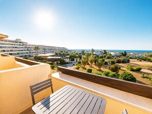 A balcony with a table and chair, overlooking a resort area with buildings and a view of the sea. - Naturiste Cap d'Agde Port Nature 740 (Agde)