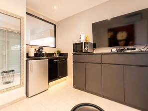 Eine moderne Küche mit integriertem Mikrowellenherd, Kaffeemaschine und Flachbildfernseher.