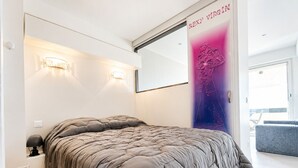A modern bedroom with a large bed, two wall-mounted lights, a large mirror, and a poster on the wall. - Naturiste Cap d'Agde Port Nature 740 (Agde)