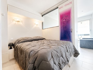 Ein modernes Schlafzimmer mit einem großen Bett, zwei Wandleuchten, einem großen Spiegel und einem Poster an der Wand.
