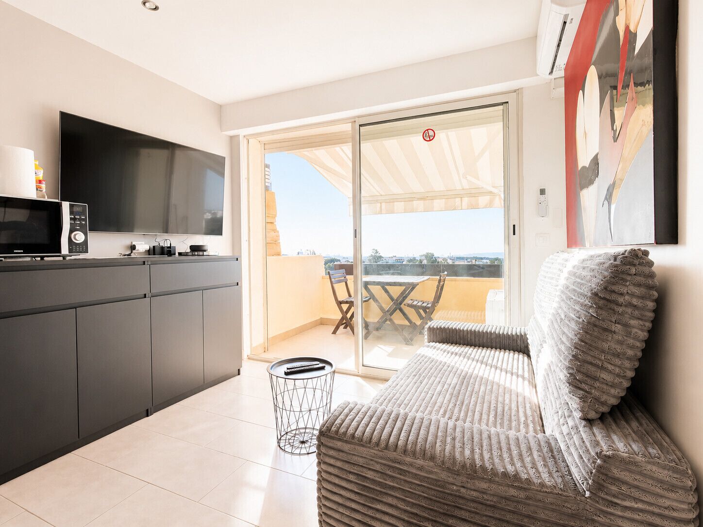 Eine moderne Küche mit Flachbildfernseher, Mikrowelle und Essecke mit Tisch und Stühlen.