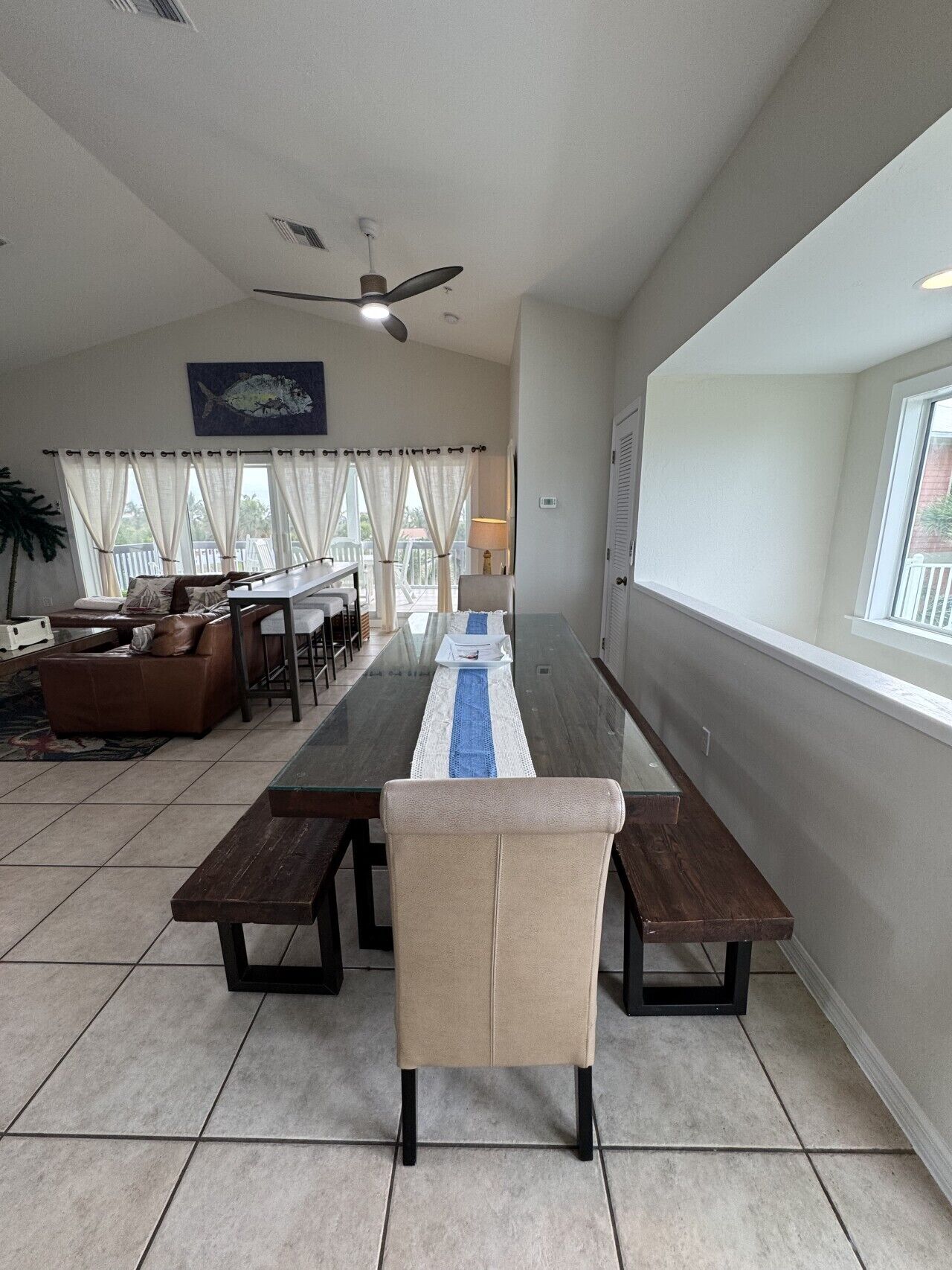 A dining area with a long table, benches, and a ceiling fan.