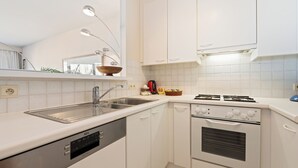 Una cucina moderna con mobili bianchi, elettrodomestici in acciaio inossidabile e forno integrato.