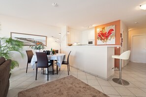 Eine moderne Küche mit weißen Schränken, einer Mikrowelle und einem Essbereich mit Tisch und Stühlen.