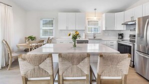 Une cuisine moderne avec des meubles blancs, un îlot central et des appareils électroménagers en acier inoxydable.