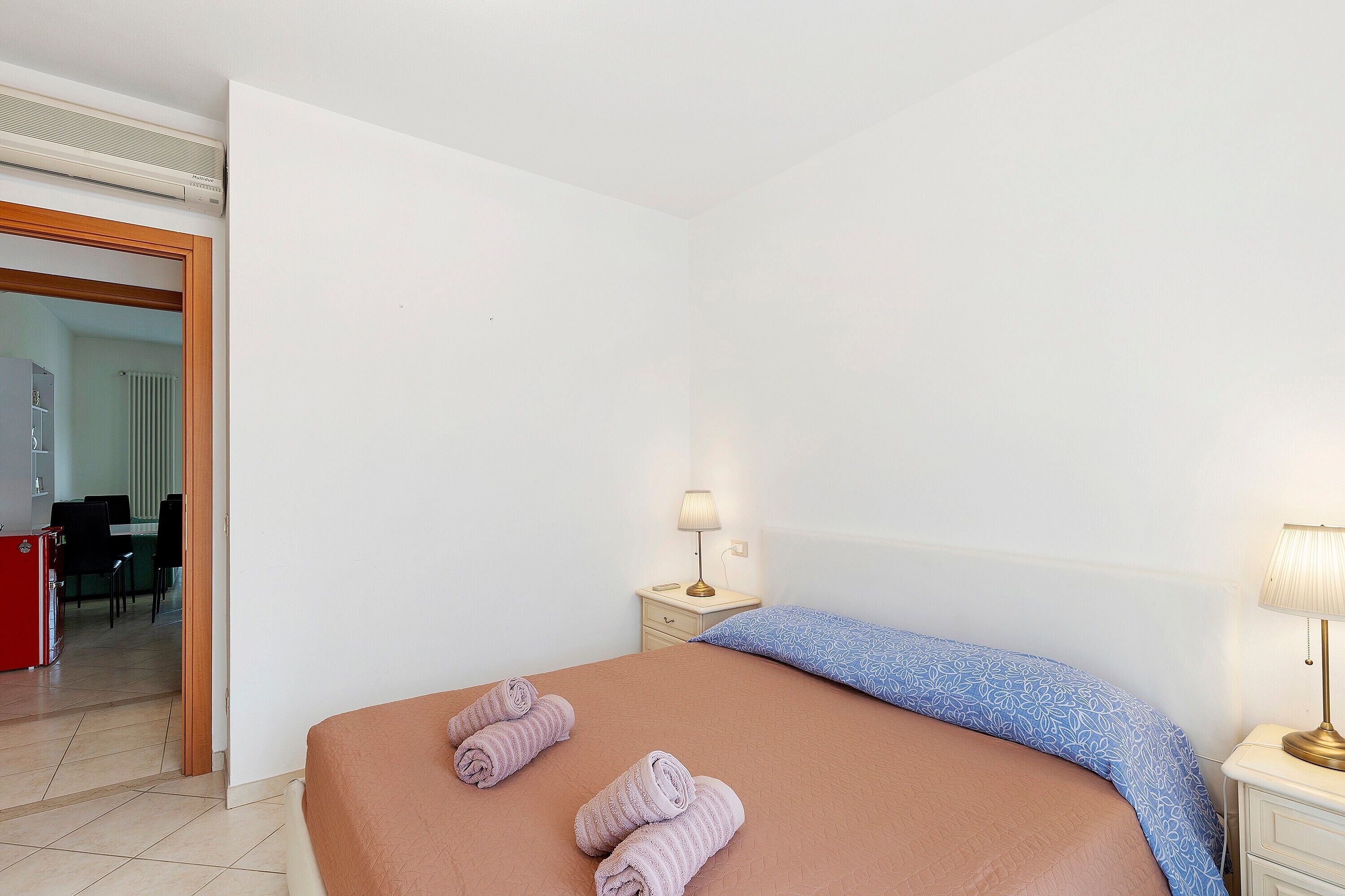 Une chambre d’hôtel avec un lit, une table de chevet avec une lampe et une vue sur la chambre voisine.