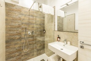 Une salle de bain moderne avec une douche à parois de verre, un lavabo blanc et un miroir au-dessus.