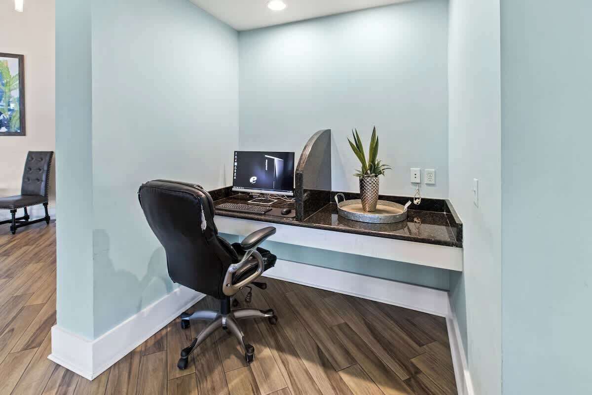Un espace de bureau moderne comprenant un bureau, une chaise, un ordinateur et une plante en pot.