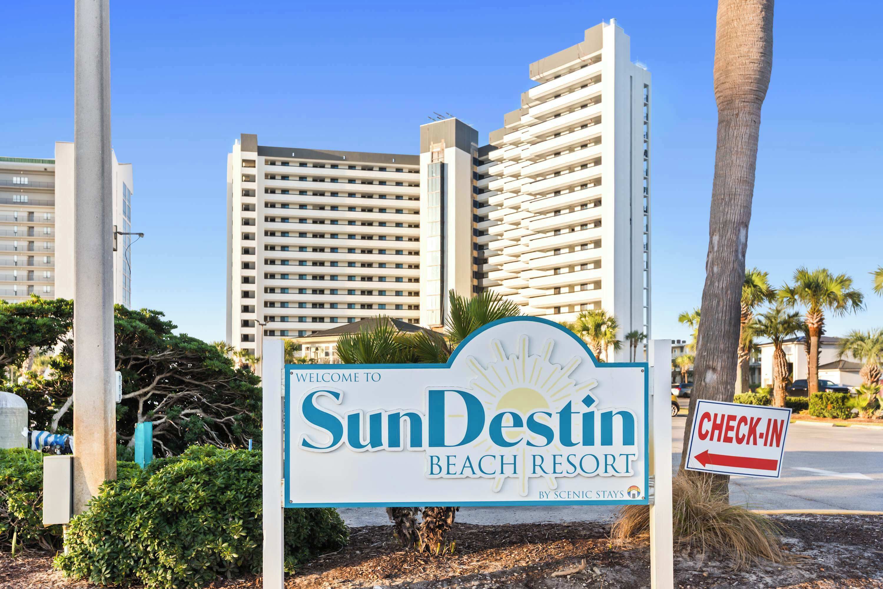Une enseigne pour le SunDestin Beach Resort, avec un ciel dégagé et des palmiers en arrière-plan.