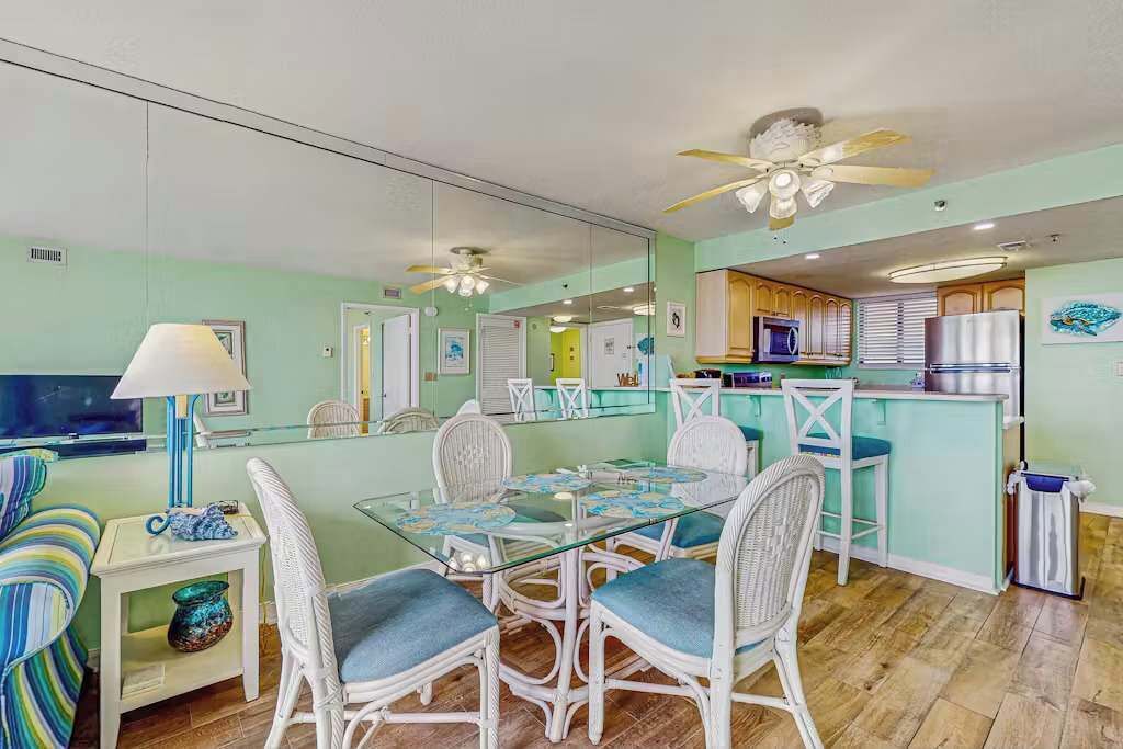 A compact living space with a dining area, kitchenette, and a mirrored wall.