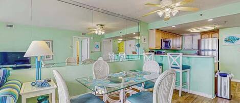 A compact living space with a dining area, kitchenette, and a mirrored wall.