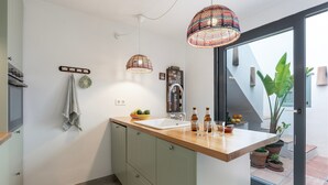 Une cuisine avec un plan de travail en bois, un évier, des serviettes suspendues et une plante en pot.