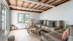 Un vaste espace de vie doté d’un plafond en bois, d’un canapé, d’un fauteuil, d’une table basse et d’une fenêtre offrant une vue agréable.
