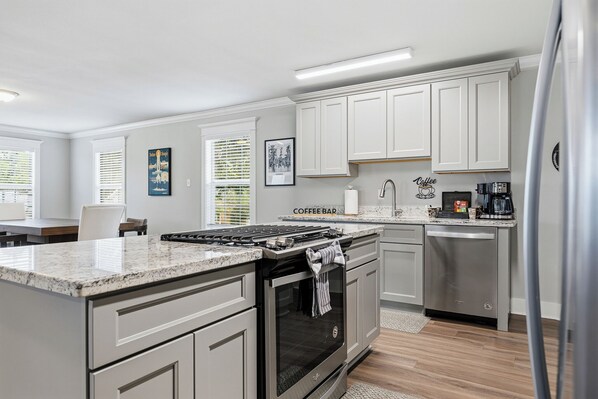 A modern kitchen with white cabinets, a built-in oven, a coffee bar, and a stainless steel refrigerator. - Garden District Luxury Oasis-Private Garage (Baton Rouge)