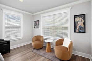 A room with two armchairs, a small round table, and a painting on the wall.
