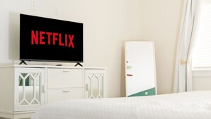 Ett hotellrum med en säng, en tv som är monterad på ett skåp och en vit garderob.