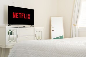 Una camera d'albergo con un letto, una TV montata su un mobile e un armadio bianco.