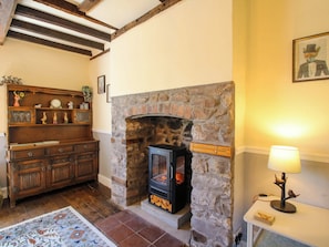 A cozy room with a stone fireplace, wooden furniture, and a lamp on a side table. - Beach Farmhouse (Bishops Castle)
