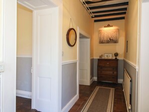 A hallway with a wooden floor, a radiator, a dresser, and a framed picture on the wall. - Beach Farmhouse (Bishops Castle)